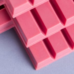 Pink chocolate bar squares on white background